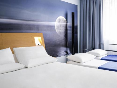 a hotel room with two beds with white pillows at Novotel Saclay in Saclay