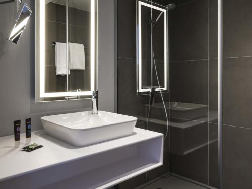 a bathroom with a white sink and a shower at Novotel Saclay in Saclay