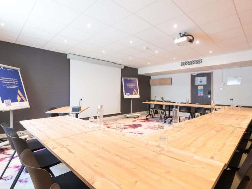 a large conference room with a large wooden table at Novotel Saclay in Saclay