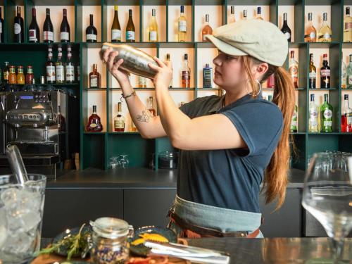 a woman standing at a bar pouring a drink at Mercure Aix en Provence Beaumanoir in Aix-en-Provence