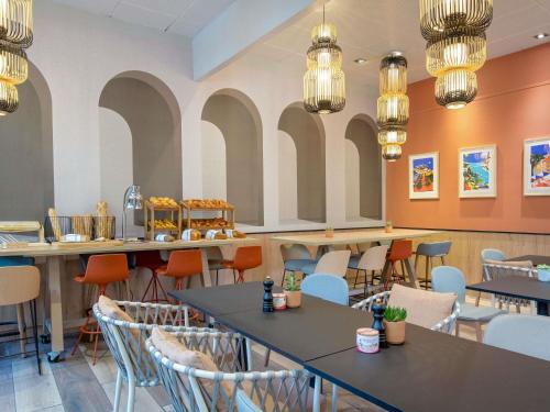 a dining room with tables and chairs and chandeliers at Novotel Aix-en-Provence Pont de L'Arc in Aix-en-Provence