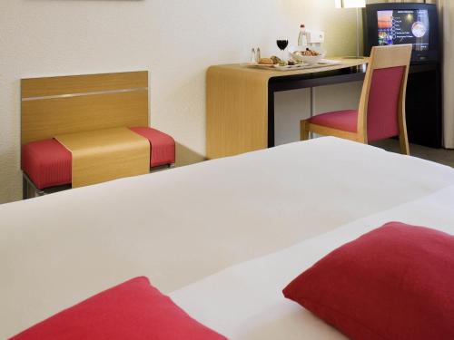 a hotel room with a bed and a table and chairs at Novotel Amiens Pôle Jules Verne in Boves