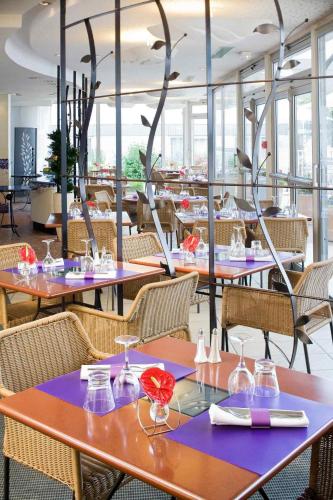 a restaurant with tables and chairs and birds flying overhead at Novotel Amiens Pôle Jules Verne in Boves