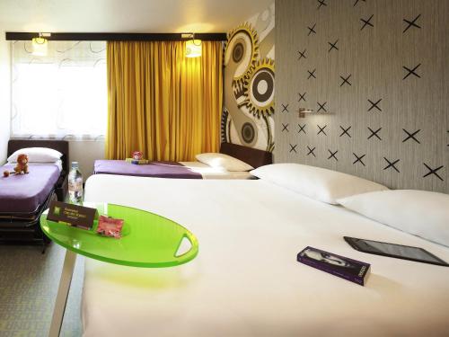 a hotel room with two beds and a green tray on a bed at ibis Styles Besançon in Besançon