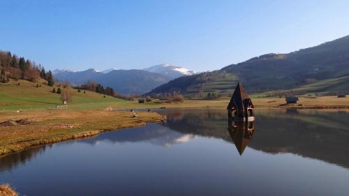 a small church on a lake with mountains in the background at Ferienhaus-Römerthurm in Schöder