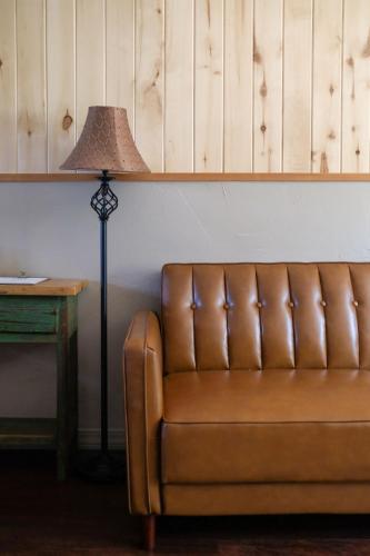 a brown leather couch next to a table with a lamp at Rocky Mountain Inn in Paonia