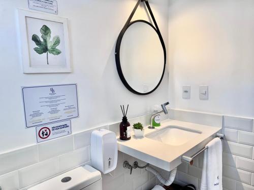 a white bathroom with a sink and a mirror at Bella Buzios Apartamentos in Búzios