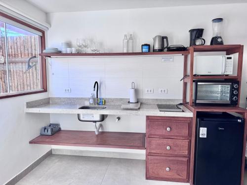 a kitchen with a sink and a microwave at Bella Buzios Apartamentos in Búzios
