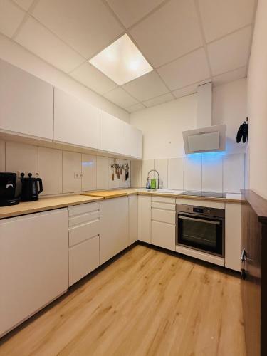 a large kitchen with white cabinets and wooden floors at Emilbnb in der Monheimer Straße in Monheim