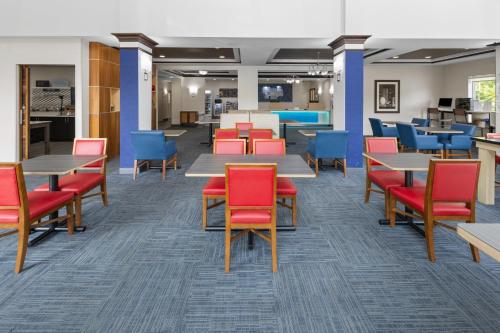 a waiting area with tables and chairs in a cafeteria at Holiday Inn Express Hotel & Suites Hamburg by IHG in Hamburg