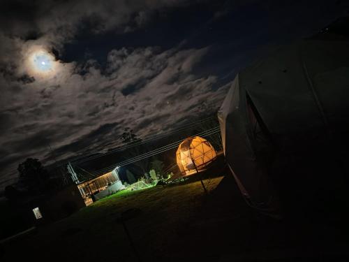 a lit up umbrella in a field at night at Glamping Ecoturistico La Villa in Las Tapias