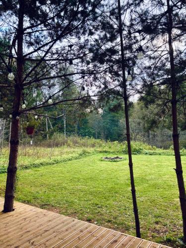 a view of a field with trees and a wooden deck at Oriküla Forest Gottage with Sauna 
