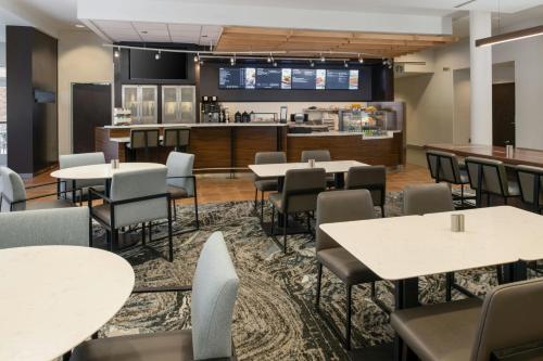 a dining room with tables and chairs and a kitchen at Courtyard by Marriott Houston City Place in Spring
