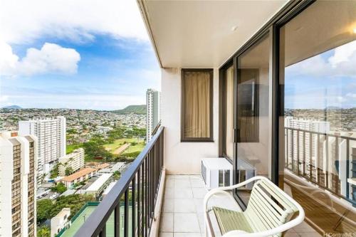 a balcony with a chair and a view of a city at Waikiki Banyan #3013 - Tower 2 in Honolulu