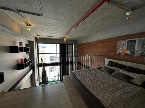 Central Medellin Modern Loft - Balcony and Transit في ميديلين: غرفة نوم بها سرير وجدار من الطوب