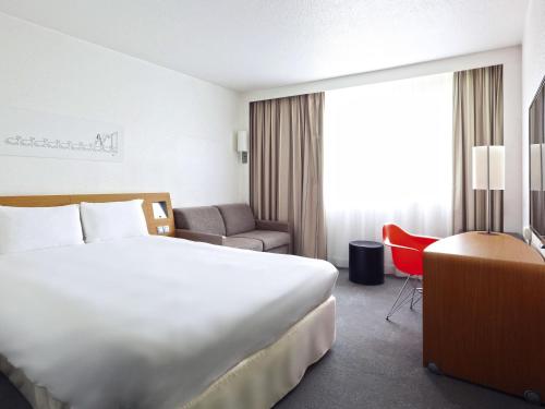 a hotel room with a large bed and a chair at ibis Styles Nancy Sud in Houdemont