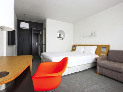 a hotel room with a bed and a desk and a chair at ibis Styles Nancy Sud in Houdemont