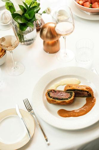 a table with a plate of food and glasses of wine at The St. Regis Belgrade in Belgrade