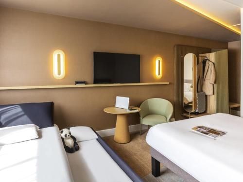 a hotel room with two beds and a tv at Novotel Nancy in Nancy