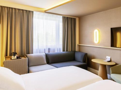 a hotel room with a couch and a bed at Novotel Nancy in Nancy