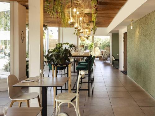 a dining room with tables and chairs and windows at Novotel Nancy in Nancy
