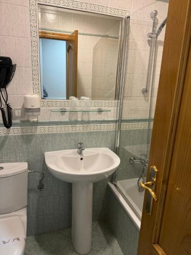 a bathroom with a sink and a toilet and a mirror at HOTEL CEAO in Lugo