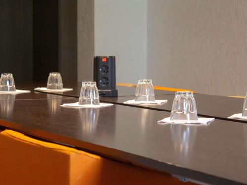 a long table with four wine glasses on it at Novotel Narbonne Sud A9/A61 in Narbonne