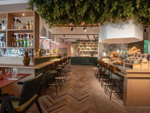 a restaurant with a long bar with stools at Novotel Nice Aéroport Cap 3000 in Saint-Laurent-du-Var