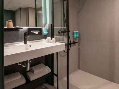 a bathroom with a sink and a shower at Novotel Nice Aéroport Cap 3000 in Saint-Laurent-du-Var
