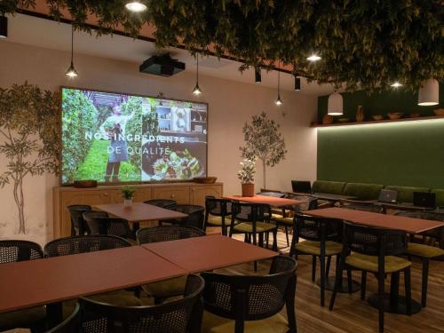 a dining room with tables and a projection screen at Novotel Nice Aéroport Cap 3000 in Saint-Laurent-du-Var