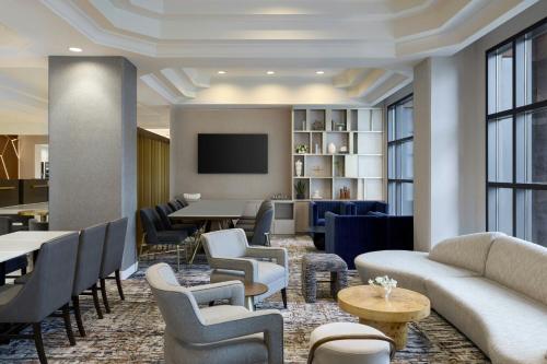 a lobby with couches chairs tables and a tv at Denver Airport Marriott at Gateway Park in Aurora