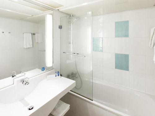 a white bathroom with a sink and a shower at Novotel Chartres in Chartres