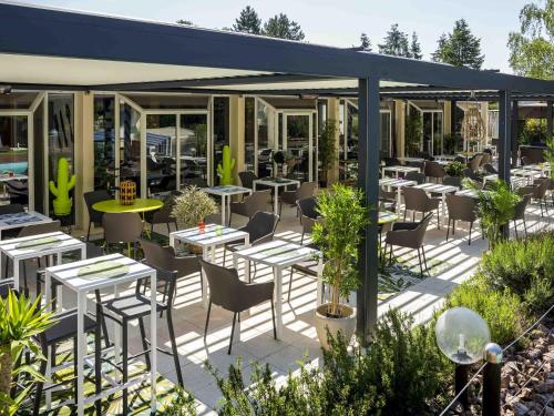 a restaurant with tables and chairs in a garden at Novotel Chartres in Chartres