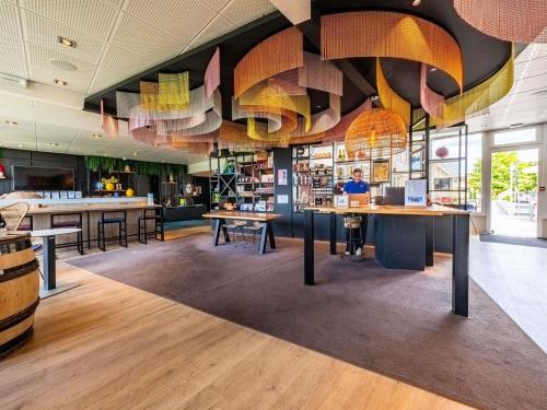 a restaurant with tables and chairs in a room at Novotel Dijon Sud in Marsannay-la-Côte