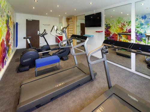 a gym with treadmills and exercise equipment in a room at Novotel Chartres in Chartres