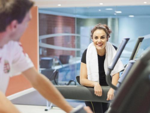 a woman with a towel around her neck sitting on a treadmill at Novotel Chartres in Chartres