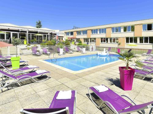 a pool with purple lounge chairs and a hotel at Novotel Dijon Sud in Marsannay-la-Côte