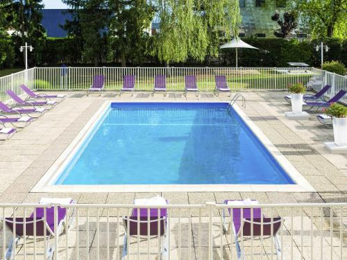 a swimming pool with purple chairs and a bunch ofitures at Novotel Dijon Sud in Marsannay-la-Côte