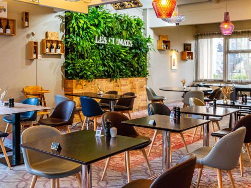 a restaurant with tables and chairs and a green wall at Novotel Dijon Sud in Marsannay-la-Côte