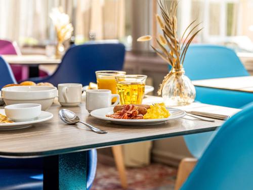 a table with a plate of breakfast food on it at Novotel Dijon Sud in Marsannay-la-Côte