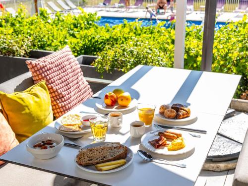 a table with plates of breakfast food on it at Novotel Dijon Sud in Marsannay-la-Côte