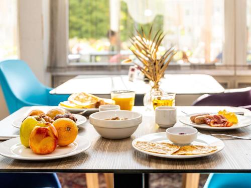 a wooden table with plates of food on it at Novotel Dijon Sud in Marsannay-la-Côte