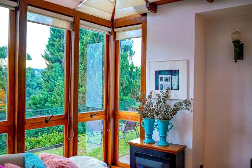 a living room with a large window and a vase with flowers at Pousada Hortelã in Campos do Jordão