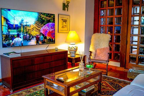 a living room with a large flat screen tv at Pousada Hortelã in Campos do Jordão