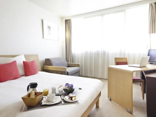 a hotel room with a bed with a tray of food on it at Novotel Pau Pyrénées in Lescar
