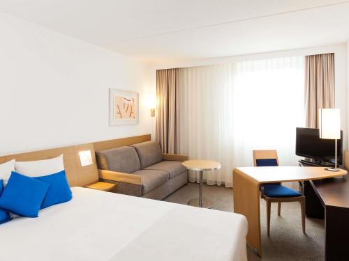 a hotel room with a bed and a couch at Novotel Pau Pyrénées in Lescar