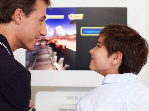 a man and a boy looking at a train on a tv at Novotel Pau Pyrénées in Lescar