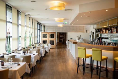 a restaurant with white tables and yellow chairs at Garner Hotel Erlangen Süd by IHG in Erlangen