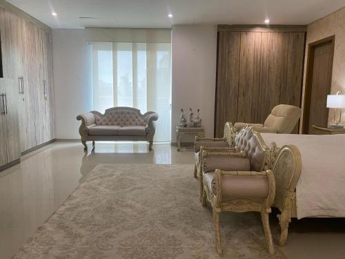 a living room with a bed and chairs and a couch at Hotel Oxford Barranquilla in Barranquilla