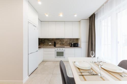 a kitchen with white cabinets and a table and chairs at Luxury Apartments Babyak in Uzhhorod